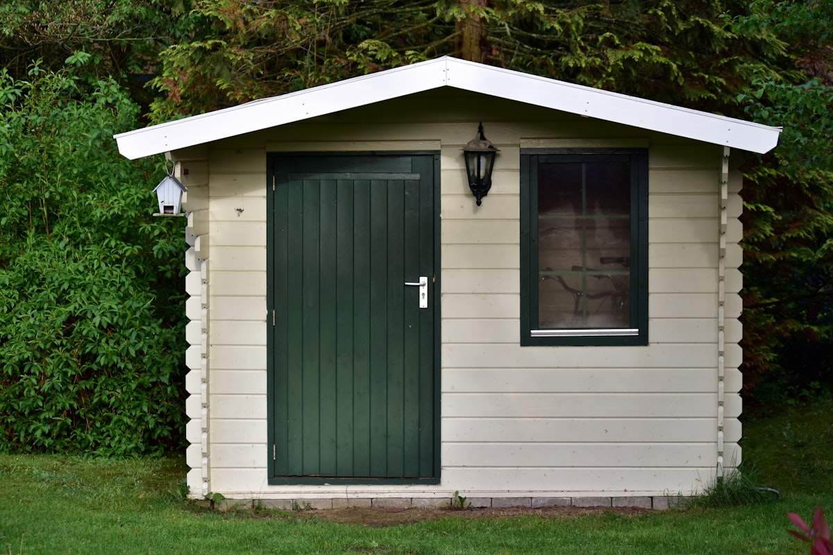 Cream garden shed with green door
